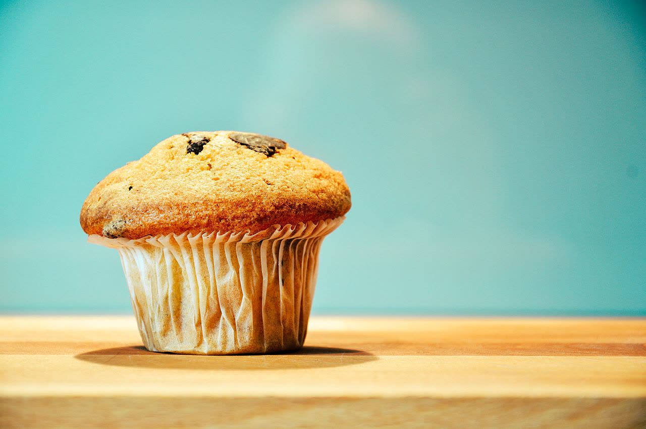Goldbraun gebackener Muffin in Papierförmchen (Symbolbild)